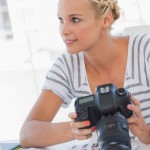Frau mit Fotoapparat vor einem Bildschirm
