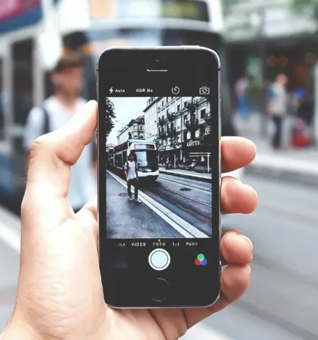 Handyfotografie: Bilder mit Iphone in der Hand fotografieren. Smartphone als Kamera. Trambahn als Hintergrund