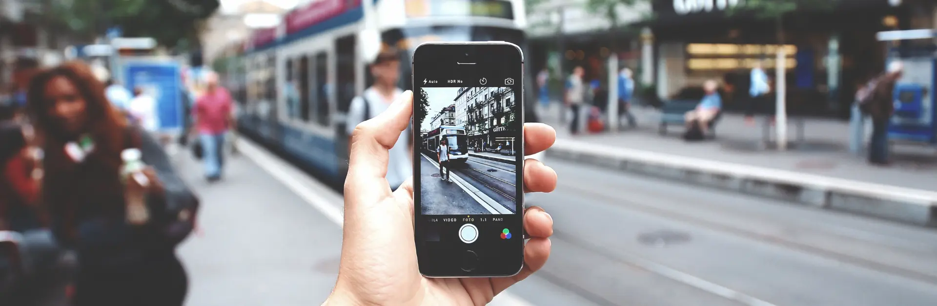 Handyfotografie: Bilder mit Iphone in der Hand fotografieren. Smartphone als Kamera. Trambahn als Hintergrund
