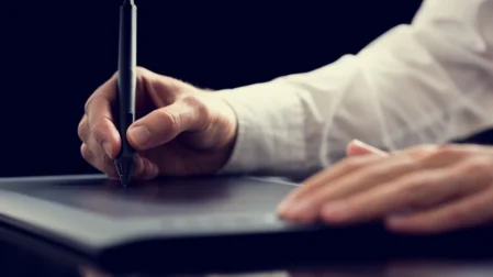 Logo erstellen auf Tablet: Männerhand hält Stift und arbeitet an Symbolen für Logos und Design.
