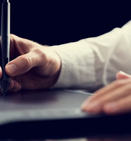 Logo erstellen auf Tablet: Männerhand hält Stift und arbeitet an Symbolen für Logos und Design.